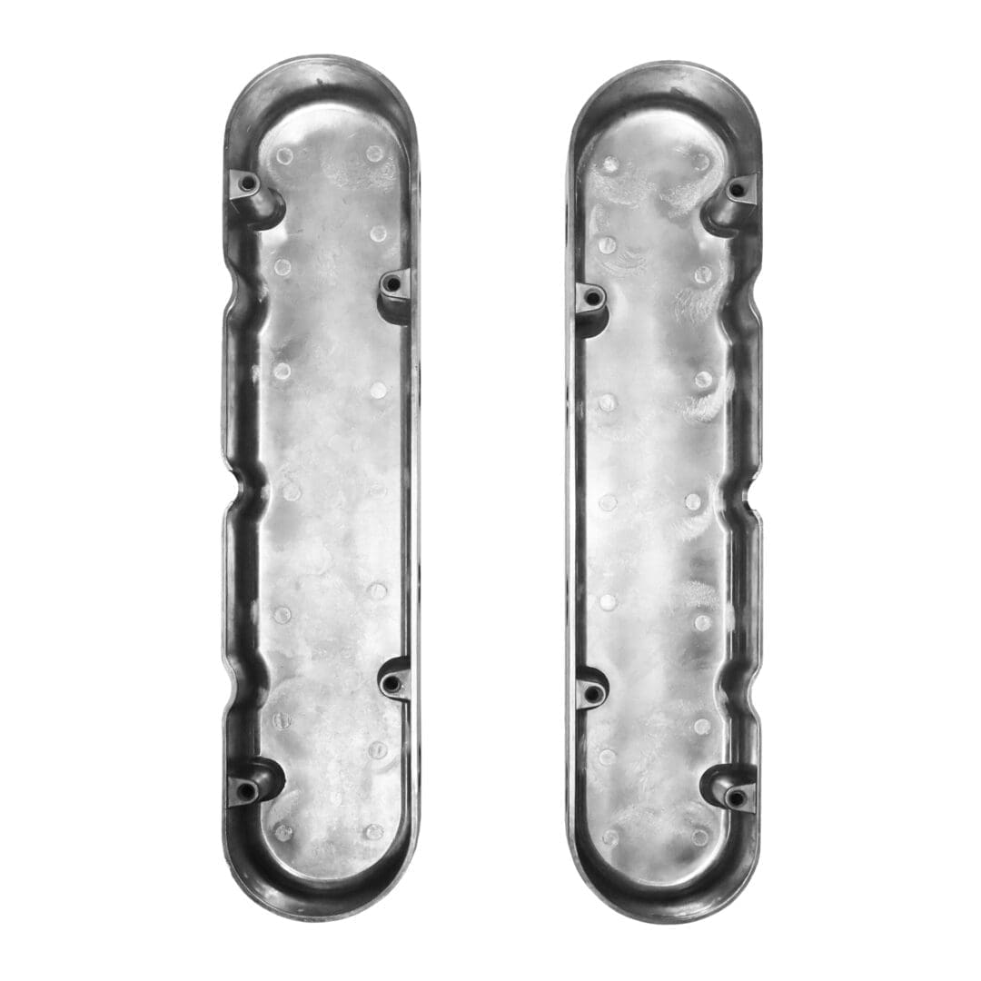 Two metal automotive valve covers, top view.